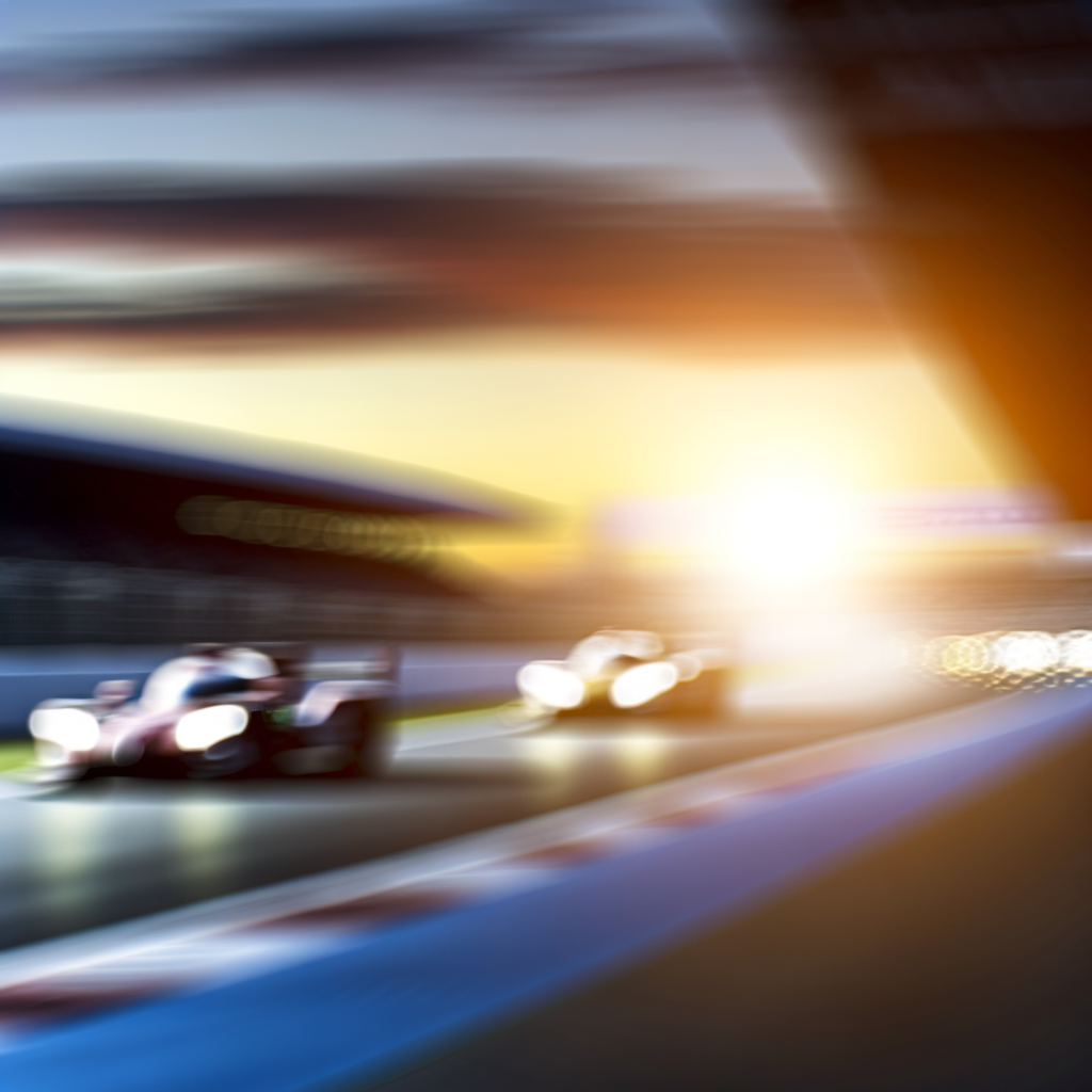 Dawn-lit racetrack with roaring race cars.